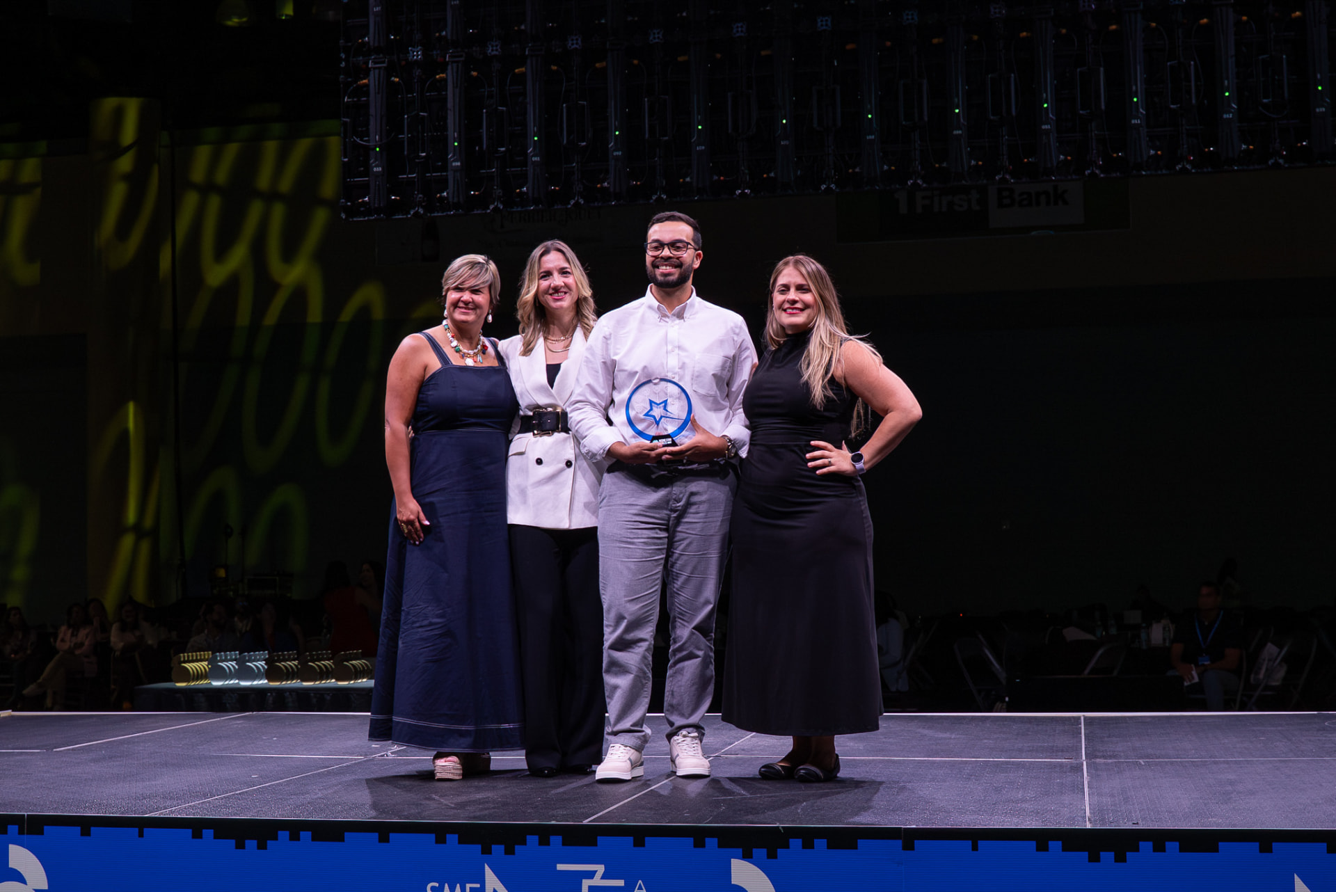 Award recipient posing with event organizers on stage