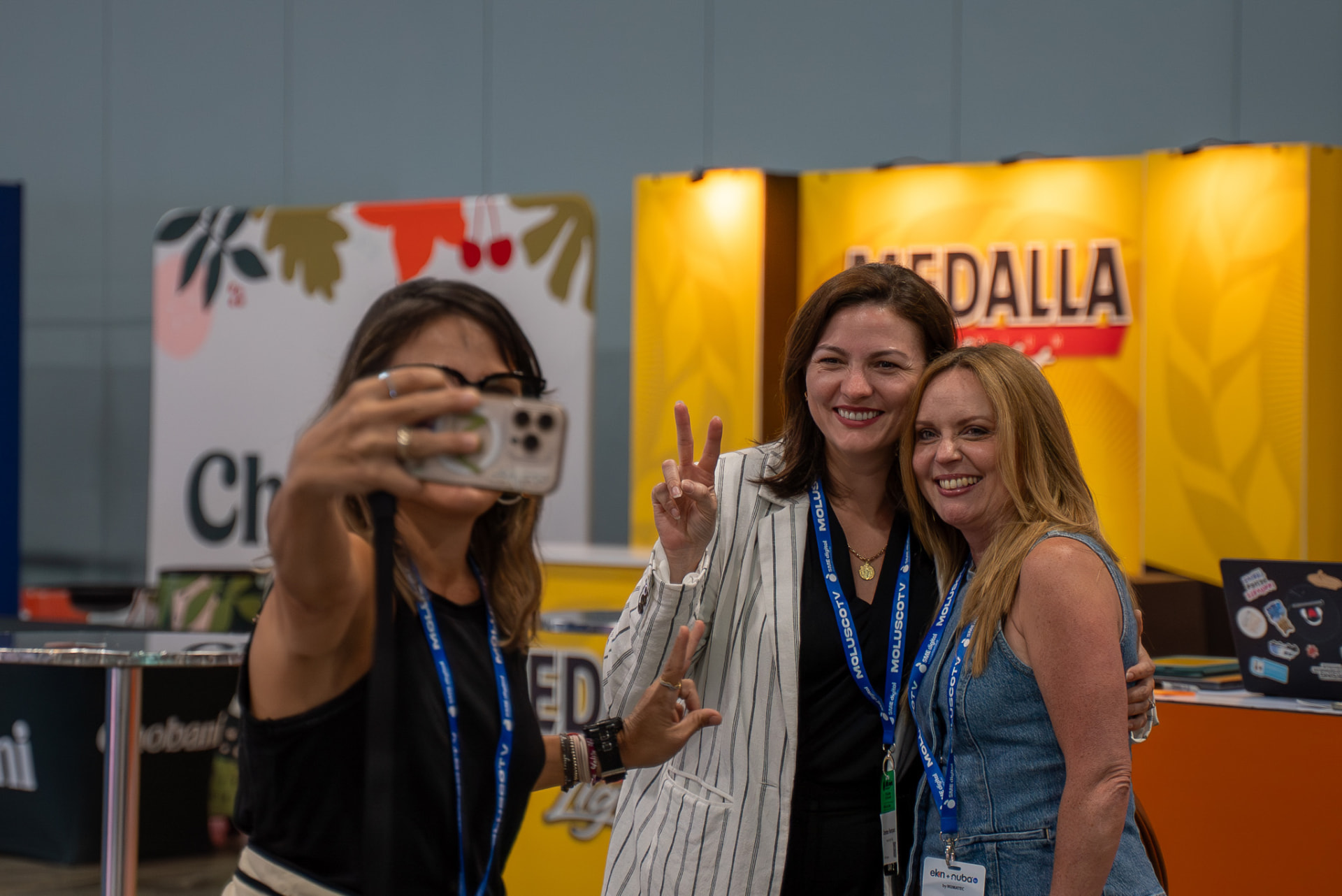 Three attendees taking a photo together at an expo